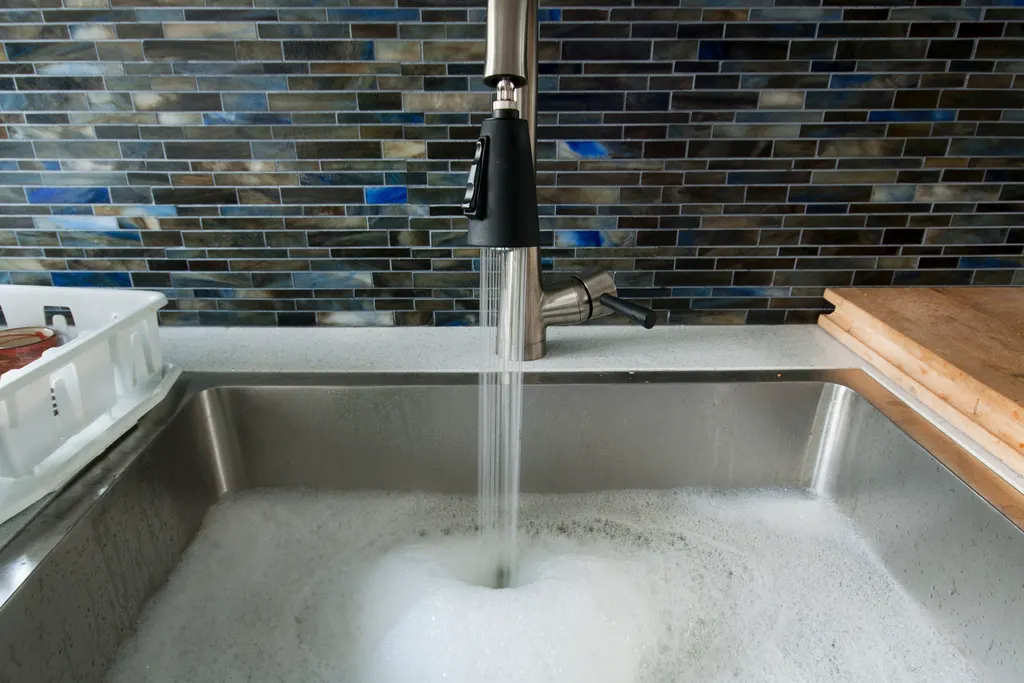 Évier de cuisine rempli d'eau savonneuse : les eaux grises de cuisine entrent dans le champ réglementaire en 2026